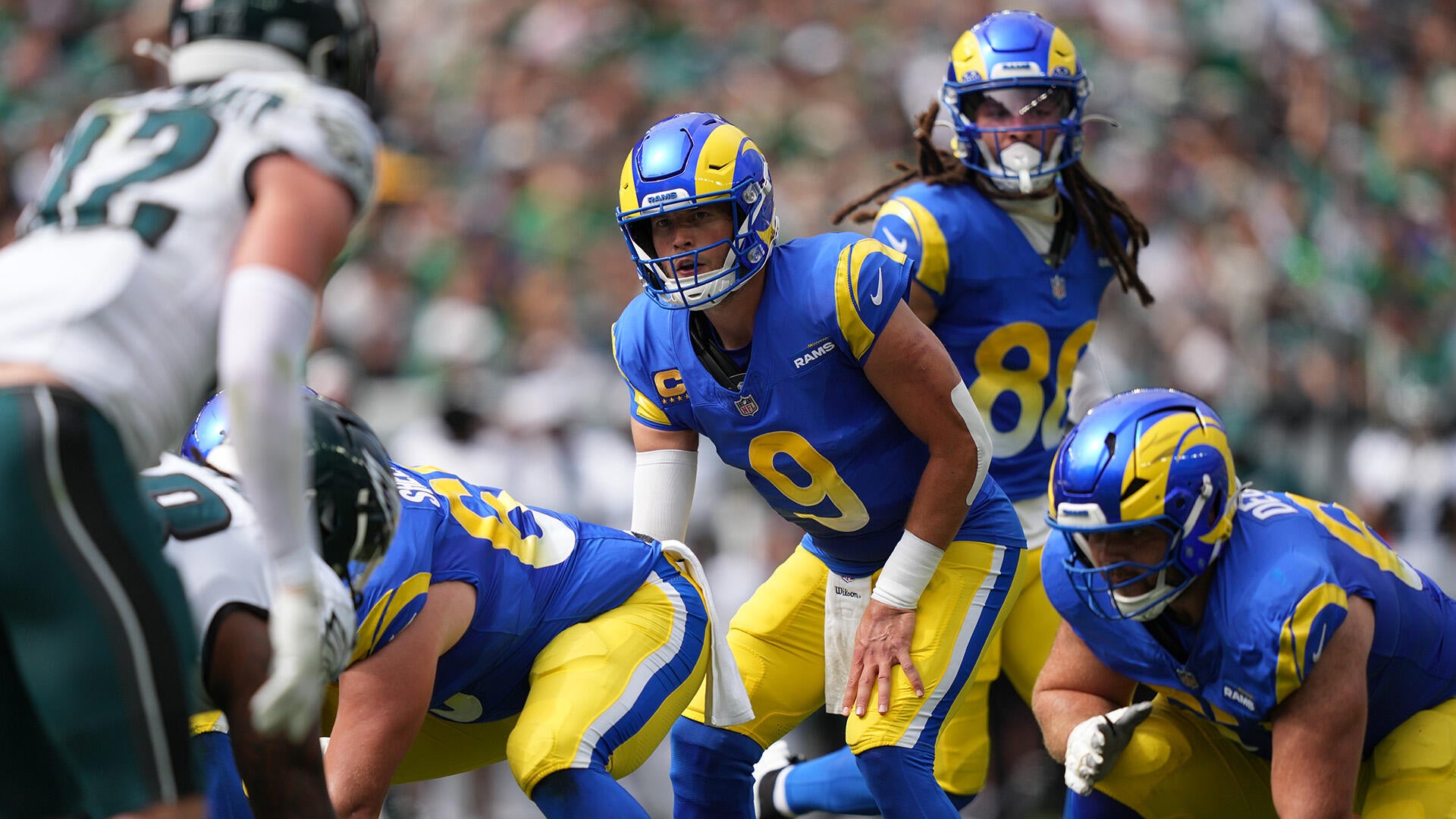 Rams QB Matthew Stafford lines up under center and makes a call while an Eagles defender watches him from across the line of scrimmage.