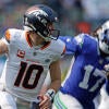 Broncos' Bo Nix, wearing a white number 10 jersey, runs with the football in his right hand while a Seahawks player chases him.