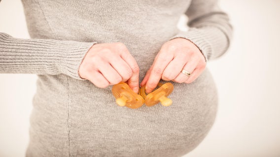 Pregnant Woman Holding two Pacifiers in her Hands