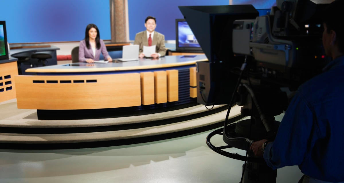 Anchor people on set in TV newsroom