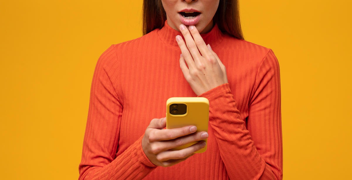 Shocked woman reading message with petrifying news on phone touching opened mouth