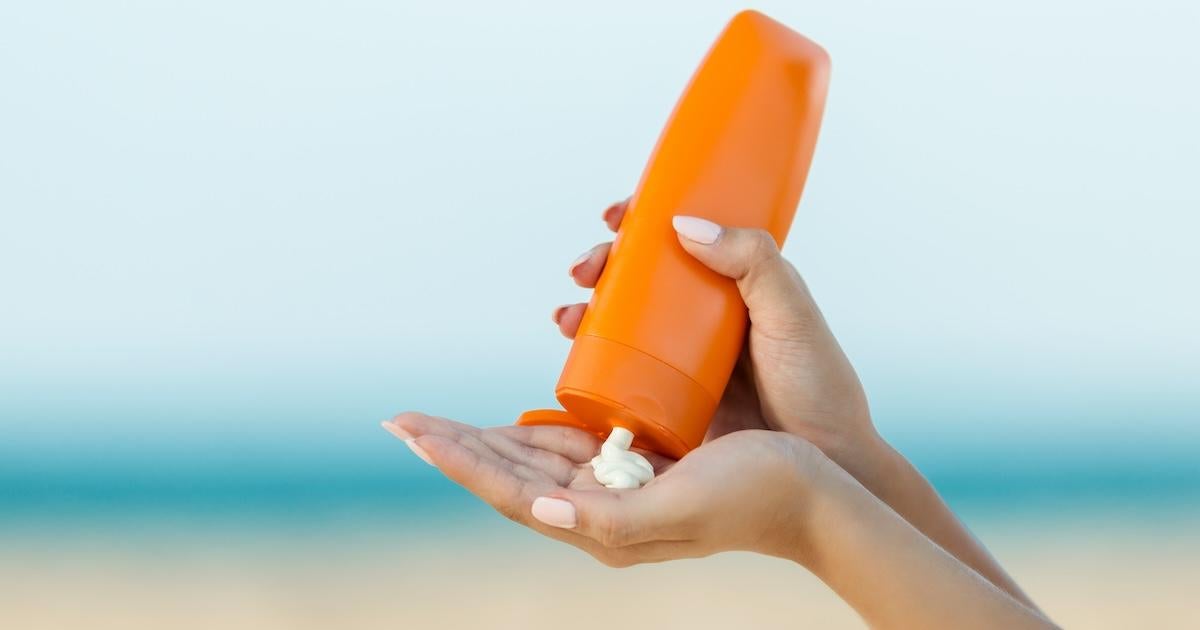 Woman hand apply sunscreen on the beach