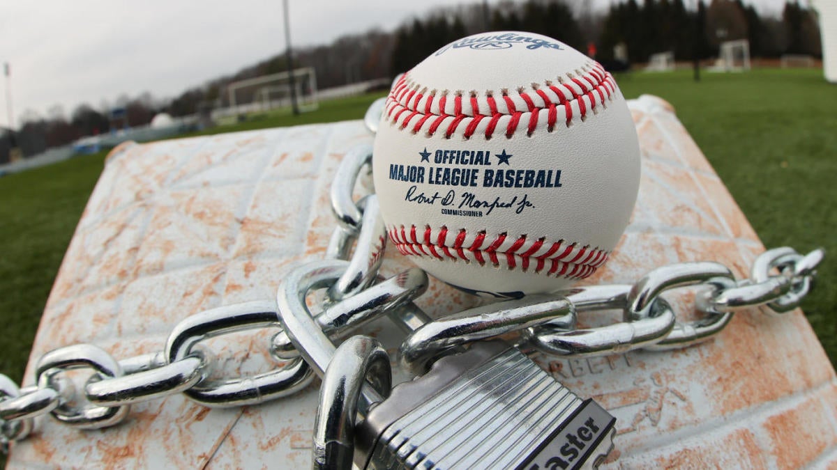 A baseball sits on a glove, with a lock and chain representing the lockout  between Major League Baseball (MLB) and the Major League Baseball Players  Association (MLBPA) on February 16, 2022, in