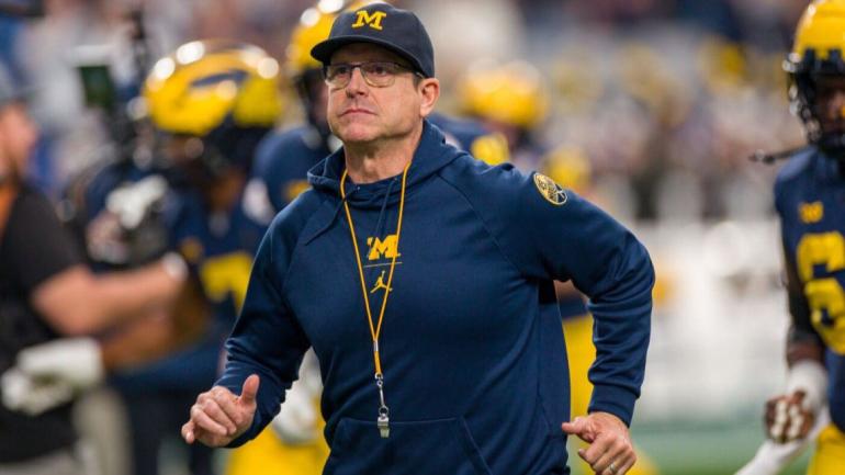 PERHATIKAN: Pelatih Michigan Jim Harbaugh membantu petugas polisi membersihkan pohon tumbang dari jalan selama badai es