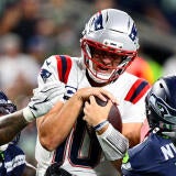 Patriots QB Drake Maye gets sacked by two Seattle defenders.