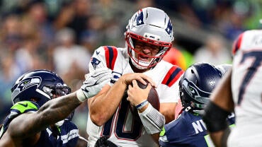 Patriots QB Drake Maye gets sacked by two Seattle defenders.