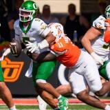 Oregon quarterback Dante Moore is sacked by Oklahoma State defensive end Keviyan Huddleston as the Oregon Ducks face the