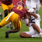 Oregon quarterback Dante Moore is hit after sliding by USC linebacker Desman Stephens II as the Oregon Ducks face the USC