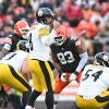 Pittsburgh QB Aaron Rodgers stands in a white jersey and makes a call at the line of scrimmage against the Cleveland Browns.