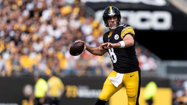 Steelers QB Aaron Rodger, wearing a black number 8 jersey, runs and attempts a pass with the football.