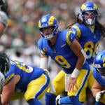 Rams QB Matthew Stafford lines up under center and makes a call while an Eagles defender watches him from across the line of scrimmage.