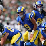 Rams QB Matthew Stafford lines up under center and makes a call while an Eagles defender watches him from across the line of scrimmage.