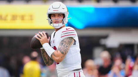 Carson Beck, wearing a white Cardinals helmet and jersey, drops back and looks to pass a football during warm ups.
